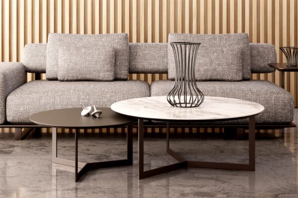 Round Opus coffee tables with marble and dark tops, in front of a fabric sofa and wooden wall panelling